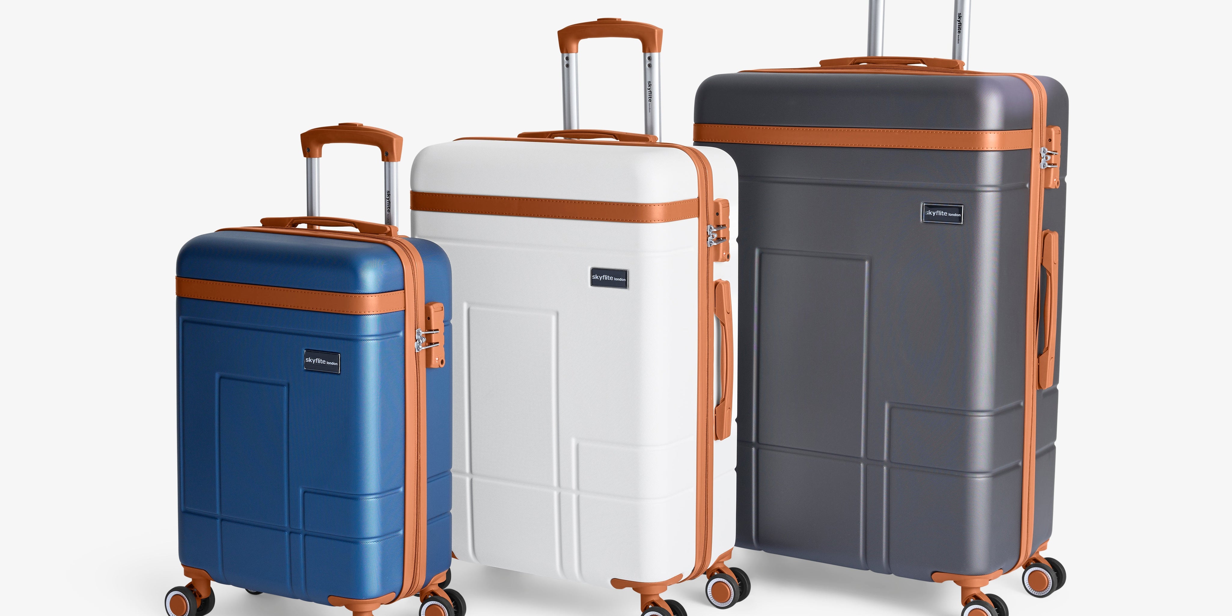 The sleek Skyflite Koncept luggage collection, showing three charcoal hard-shell suitcases in large, medium, and cabin sizes, detailed with vintage-style tan accents.