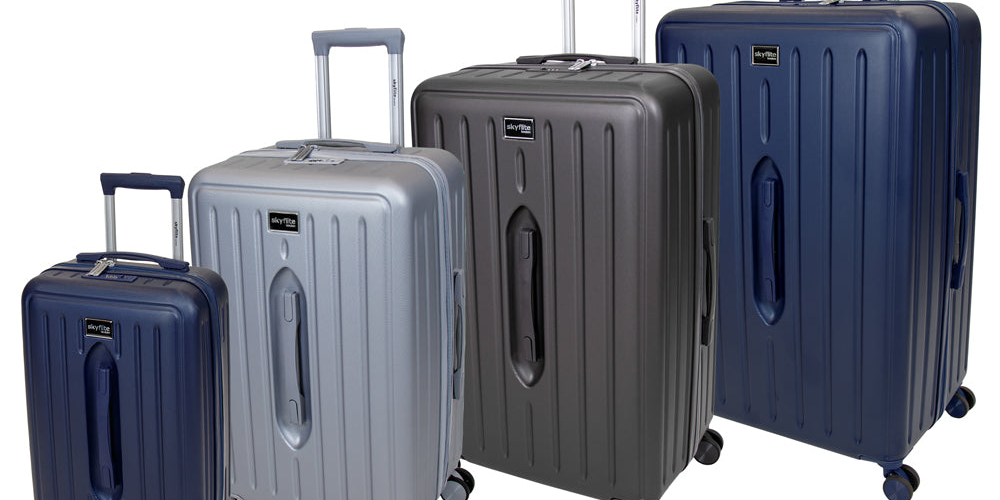 The complete Skyflite Modern Trunk luggage collection, featuring four off-white contemporary hard-shell cases with tan strap details, lined up from largest to smallest.