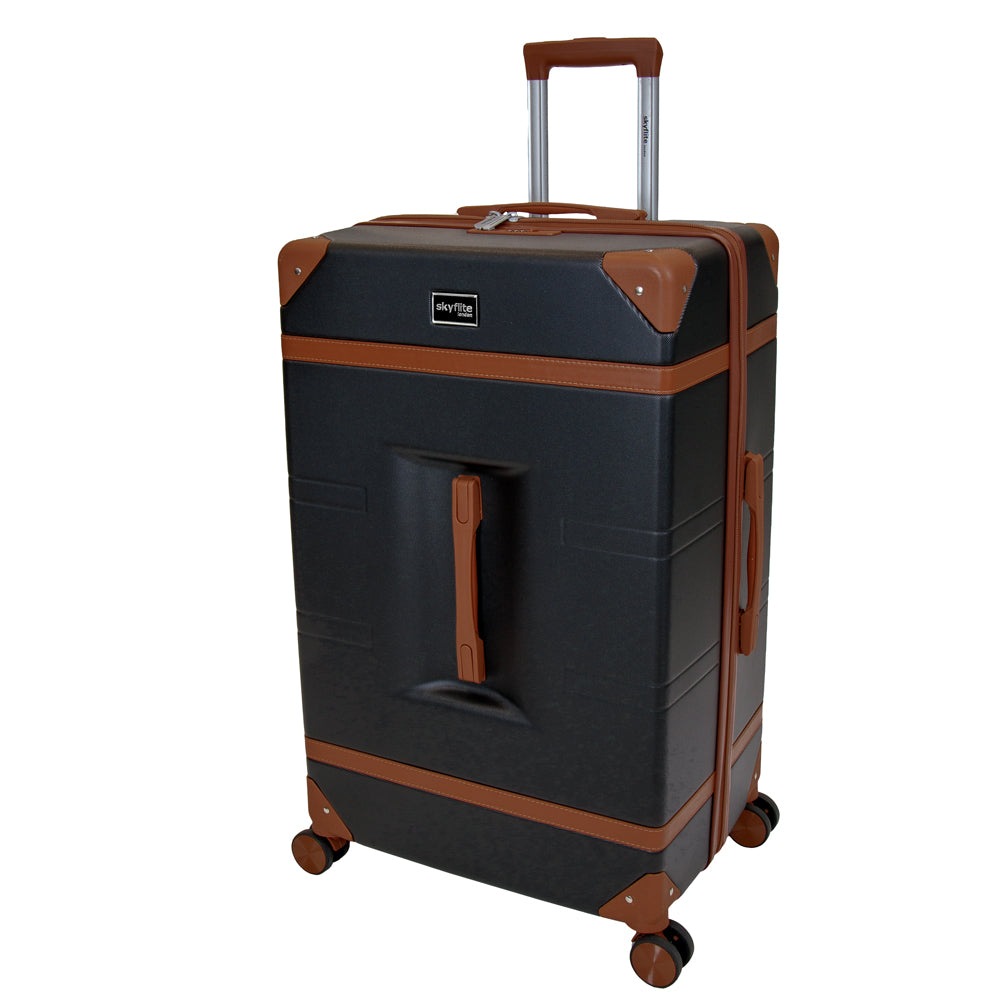 The large black Skyflite Retro Trunk hardshell suitcase shown from the front, with its telescoping handle extended and four 360° spinner wheels.